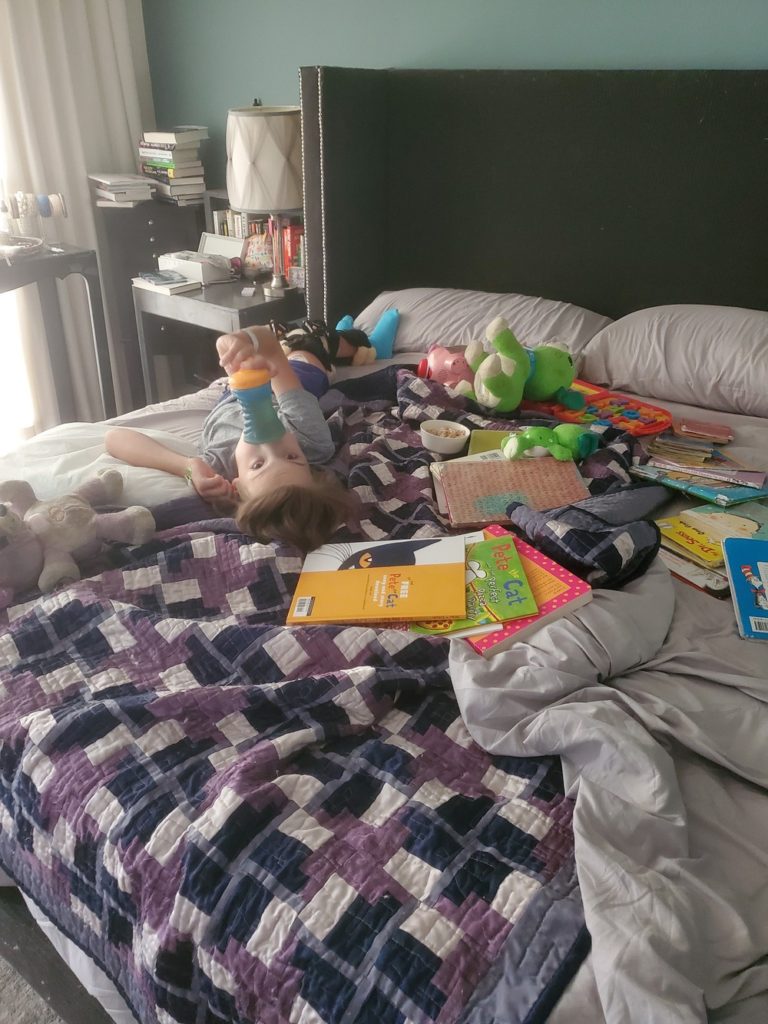 Atticus recovering from surgery by playing in bed surrounded by all his favorite toys.